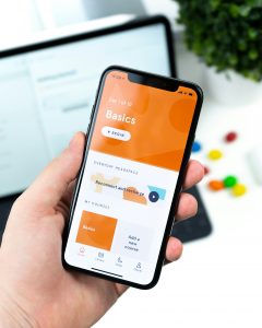 Ein Smartphone zeigt eine geöffnete Achtsamkeits-App mit klar strukturierter Benutzeroberfläche, im Hintergrund ist ein unscharfer Laptop sichtbar.