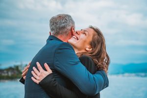 Eine herzliche Umarmung zwischen zwei Menschen am See vermittelt Lebensfreude und Nähe.