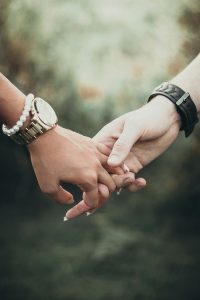 Zwei Menschen halten sich liebevoll an den Händen, ein Symbol für Vertrauen und gegenseitige Unterstützung.