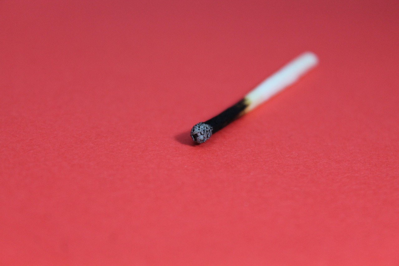 Ein abgebranntes Streichholz liegt auf rotem Hintergrund – Symbol für emotionale Erschöpfung. Viele Menschen mit ADHS Schweiz erleben eine erhöhte Anfälligkeit für Burnout durch chronische Überforderung. Dieses Bild steht sinnbildlich für das Gefühl des Ausgebranntseins.