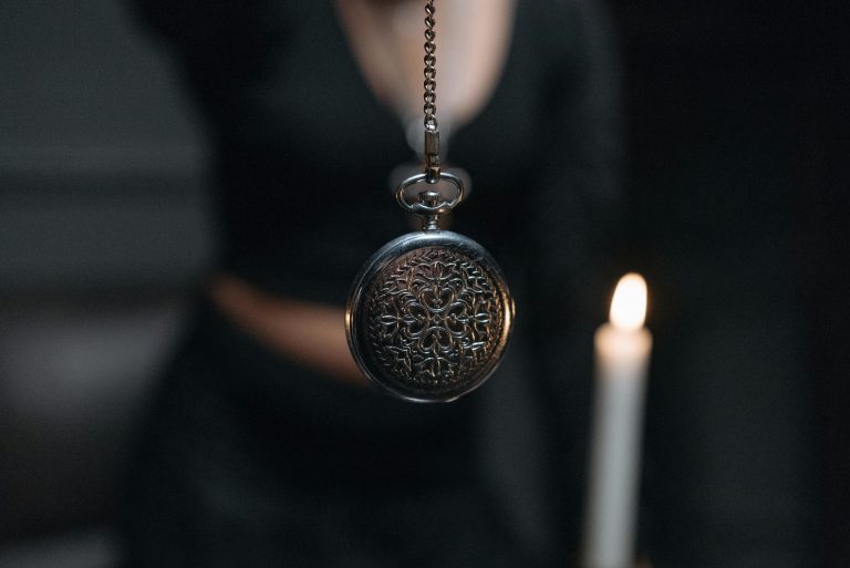 Eine antike Taschenuhr pendelt vor einer brennenden Kerze – ein klassisches Symbol der Hypnose. Dieses Bild steht exemplarisch für Methoden der ADHS Hypnose Schweiz, die auf visuelle Fokussierung setzen.
