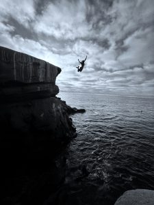 Eine Person springt von einer Klippe ins offene Meer. Das Bild steht für spontane Entscheidungen ohne lange Abwägung.
