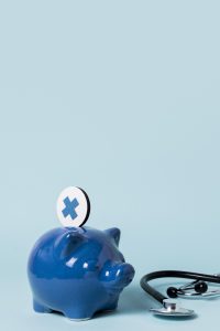 Ein blaues Sparschwein mit einem Gesundheits-Symbol und einem Stethoskop steht auf hellem Hintergrund. Das Bild steht für Gesundheitskosten und finanzielle Absicherung.