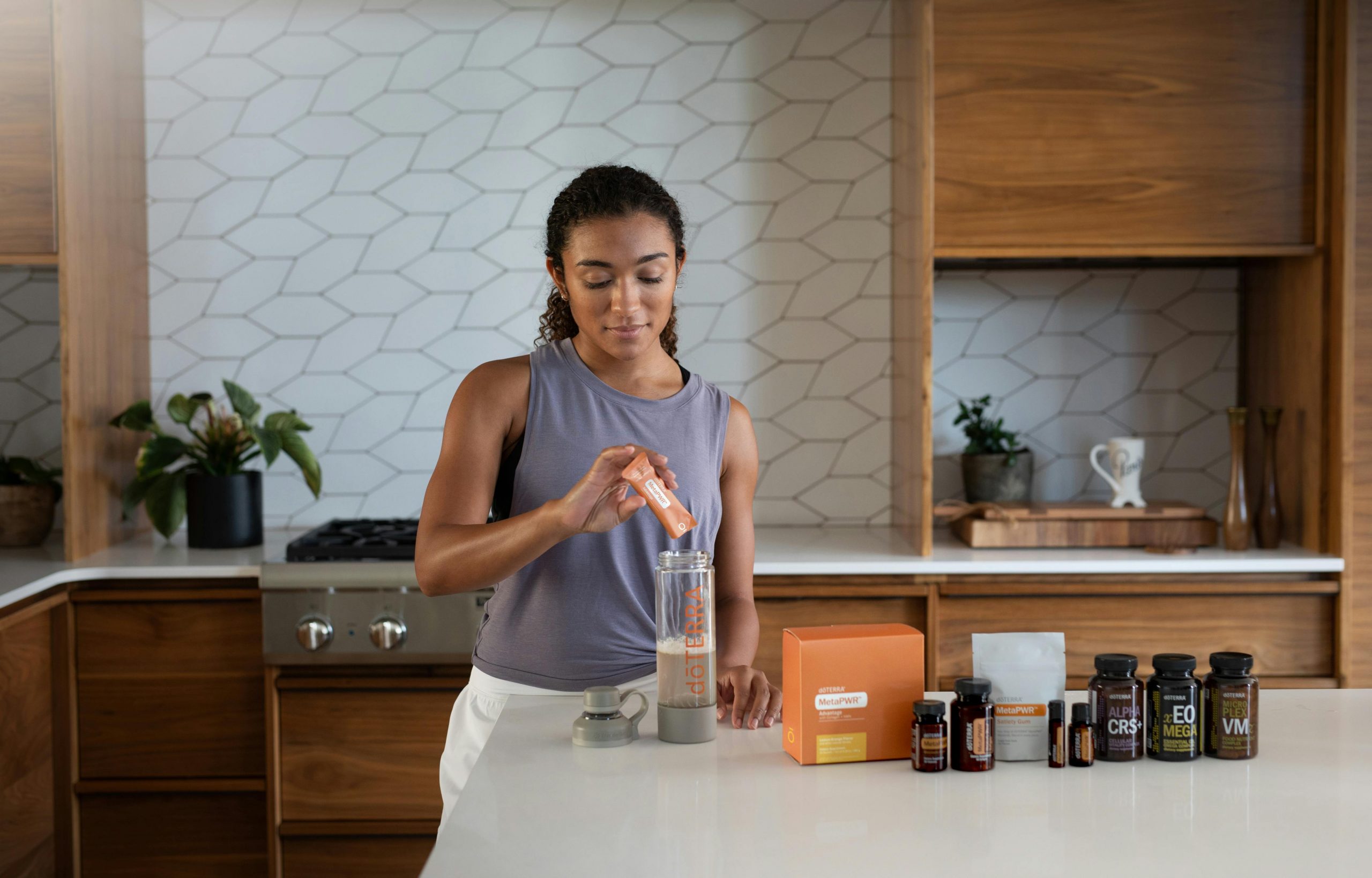 Eine Frau steht in einer modernen Küche und füllt ein Nahrungsergänzungspulver in eine Flasche. Auf der Küchenzeile sind verschiedene Supplement-Behälter aufgereiht. Eine ausgewogene Supplementierung kann Teil eines Therapiekonzepts bei ADHS Schweiz sein.