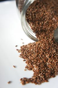 Leinsamen werden aus einem Glas auf eine helle Fläche gestreut. Omega-3-Fettsäuren sind in manchen Lebensmitteln enthalten und werden bei ADHS diskutiert.