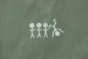 Vier Strichmännchen in einer Reihe, eines davon steht auf dem Kopf, als Metapher für neurodiverse Denkweisen bei ADHS und Autismus, die sich oft von der Norm abheben.