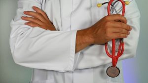 Ein Hausarzt im weissen Kittel hält ein rotes Stethoskop in der Hand. In der Schweiz ist eine ärztliche Anordnung häufig Voraussetzung für eine Psychotherapie bei ADHS. Dieses Bild symbolisiert die medizinische Begleitung beiADHS.