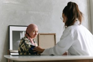 Eine empathische Ärztin misst den Blutdruck einer Patientin, die ein Kopftuch trägt. Auch beiADHS ist eine gute Hausarztbetreuung ein wichtiger Teil der Versorgung. Das Bild steht für Vertrauen und interdisziplinäre Zusammenarbeit.