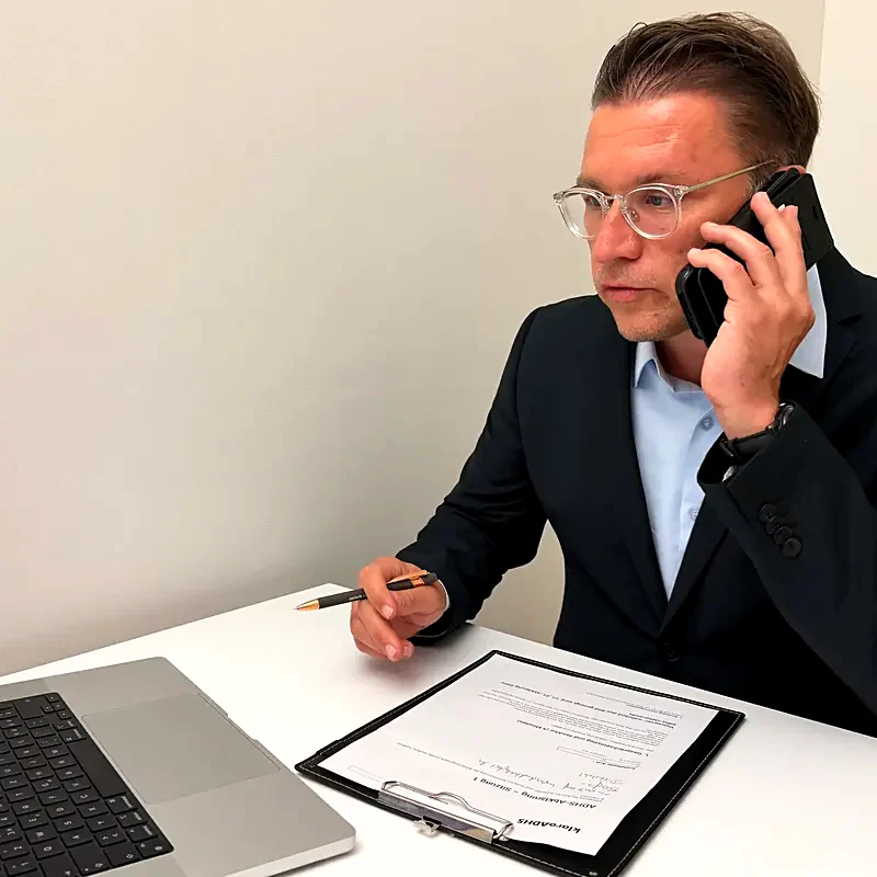 Dirk Sikorski telefoniert am Schreibtisch der klaro ADHS Praxis, vor ihm liegen Unterlagen zur Abklärung